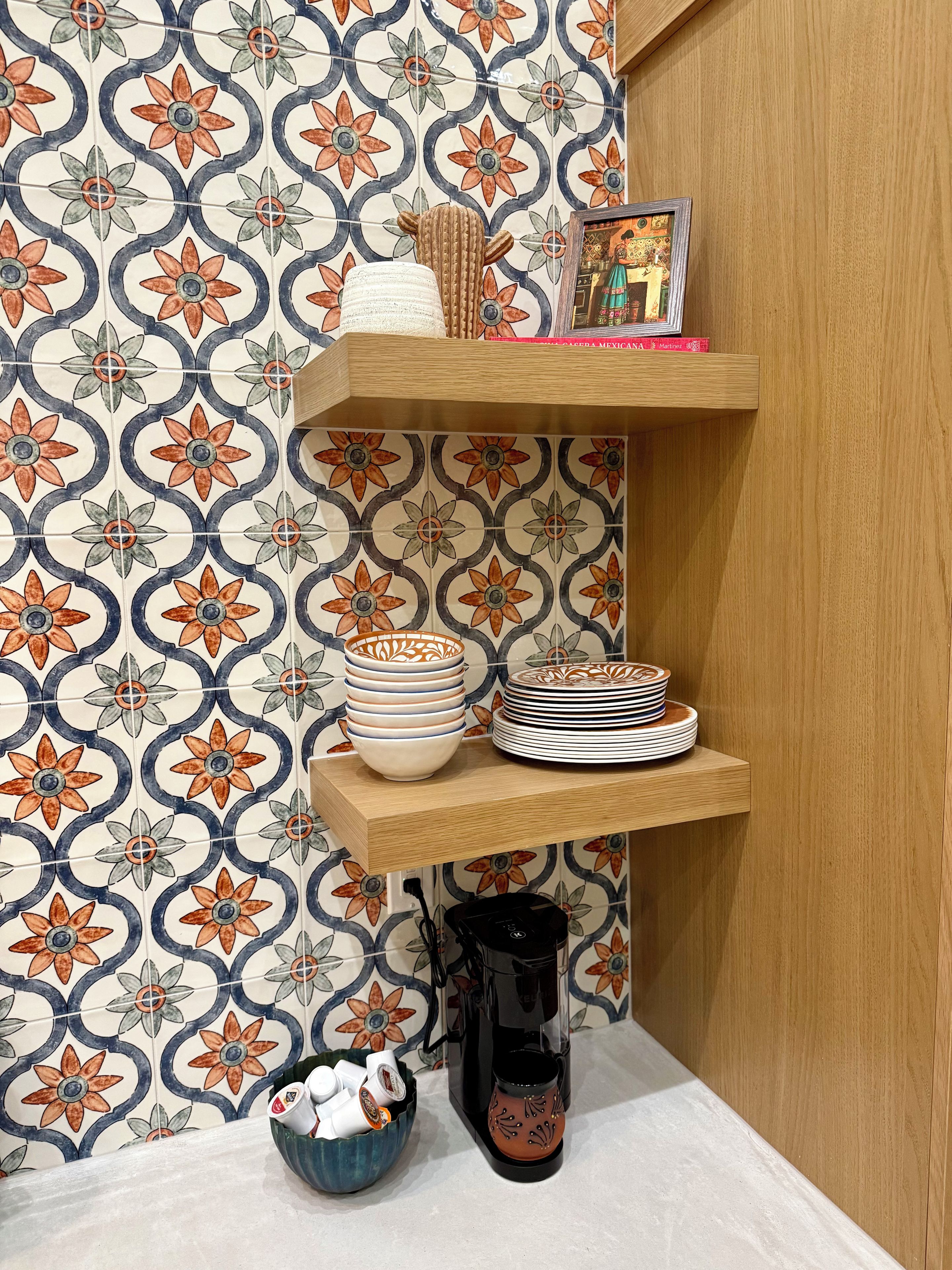 Una cocina con un salpicadero de diseño, un estante de madera con utensilios de cocina y una cafetera.