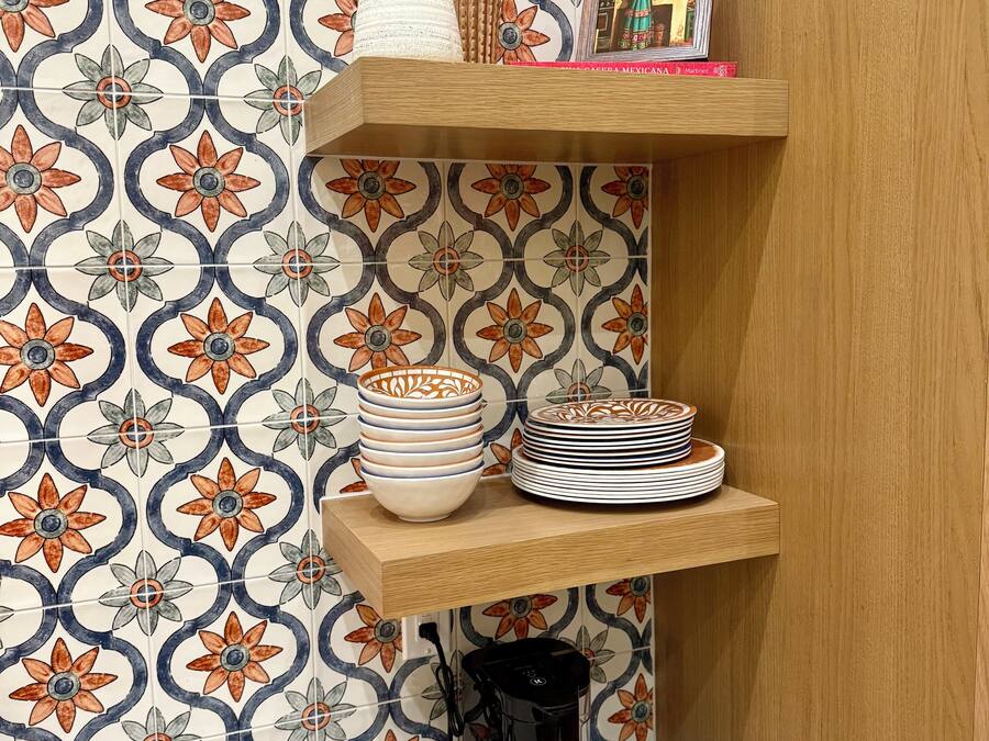 Una cocina con un salpicadero de diseño, un estante de madera con utensilios de cocina y una cafetera.