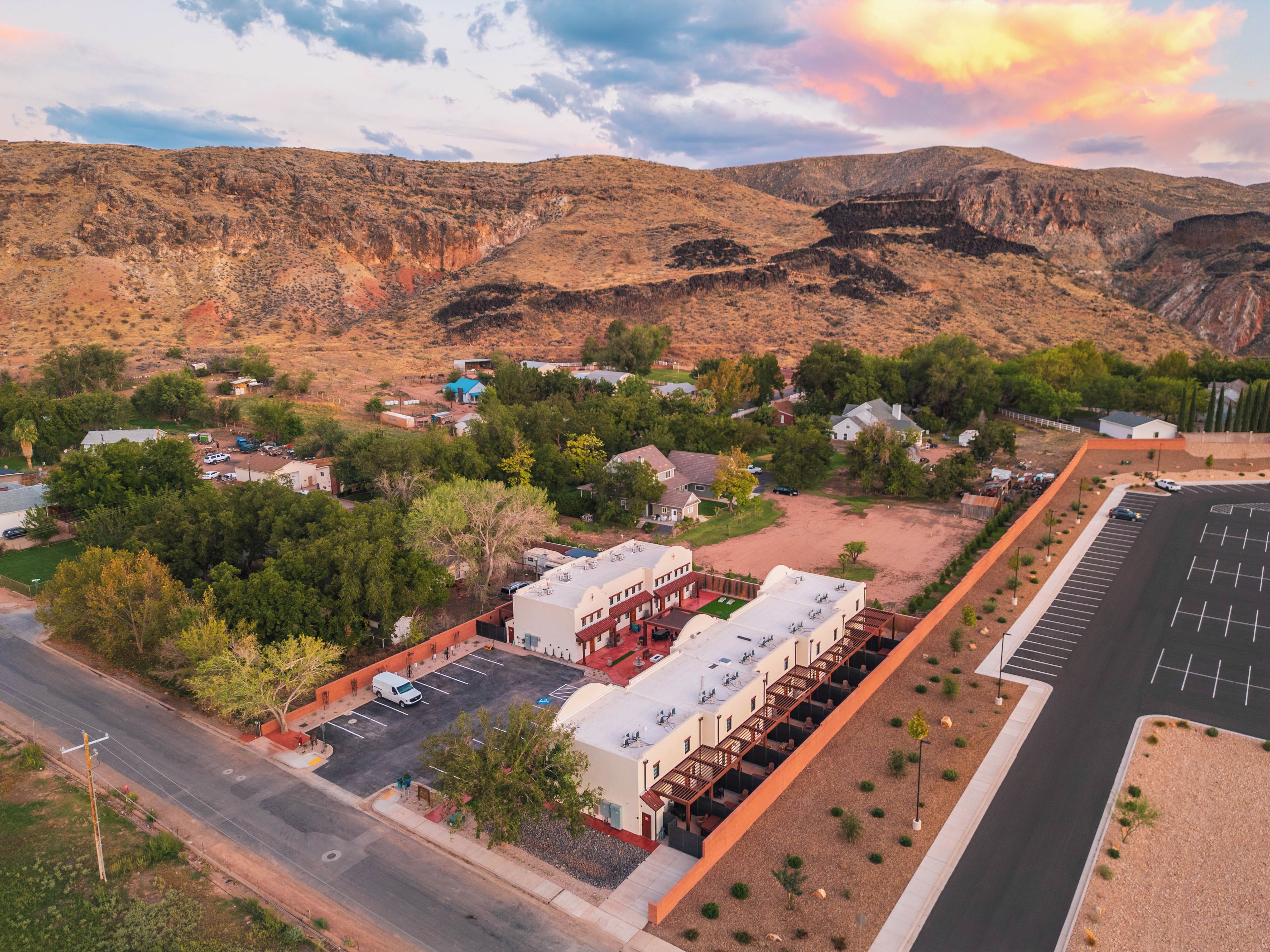A town with a main road, a parking lot, and buildings with a mix of residential and commercial properties.