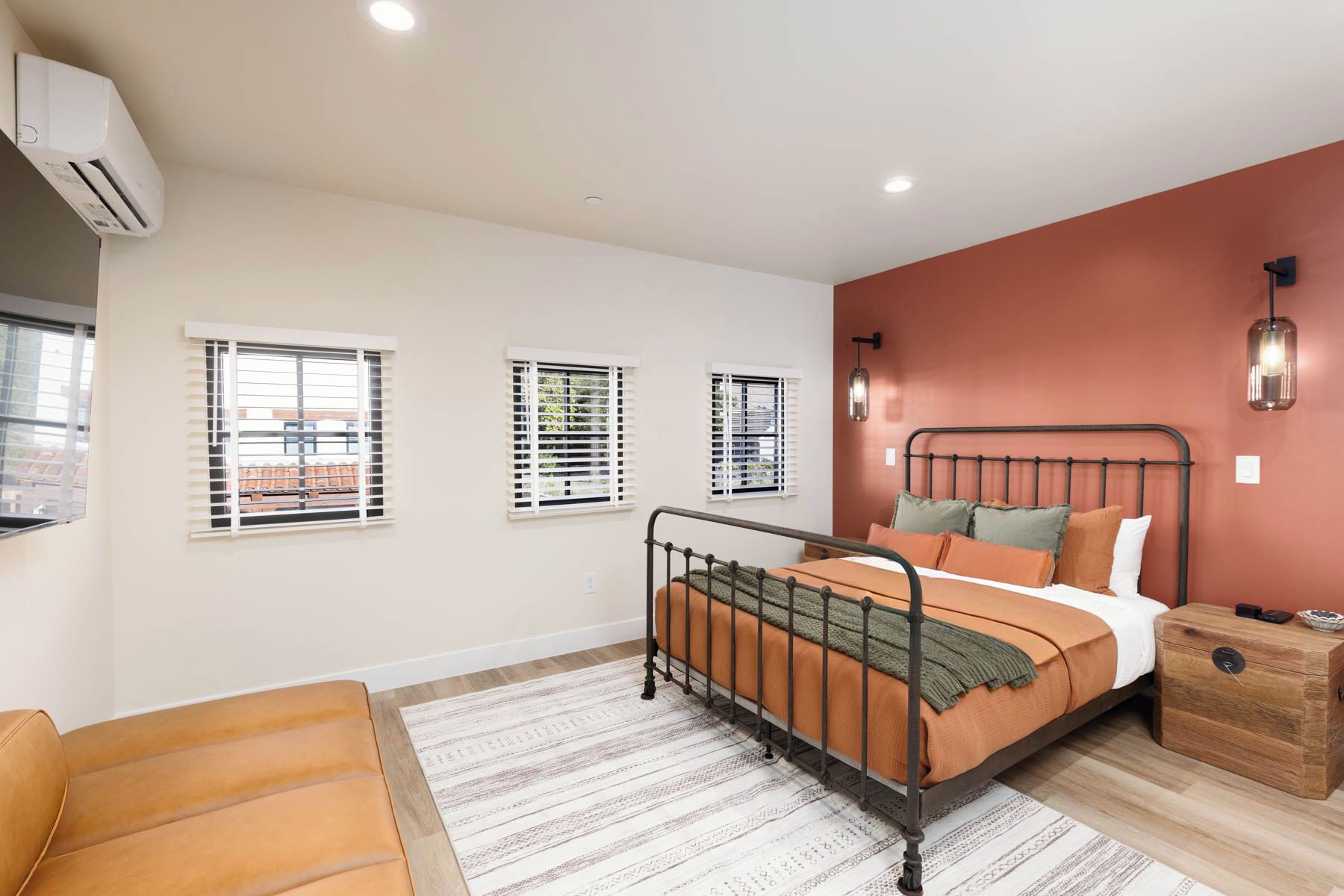 A bedroom with a metal bed frame, a wooden chest of drawers, and a sofa.