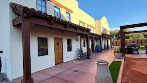 A building with a flat roof, multiple windows, and a patio area with a large planter and seating. - Casa De Hot Springs (La Verkin)