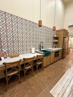 Una cocina con salpicadero de diseño, armarios de madera, un refrigerador de acero inoxidable y un comedor con mesa y sillas.