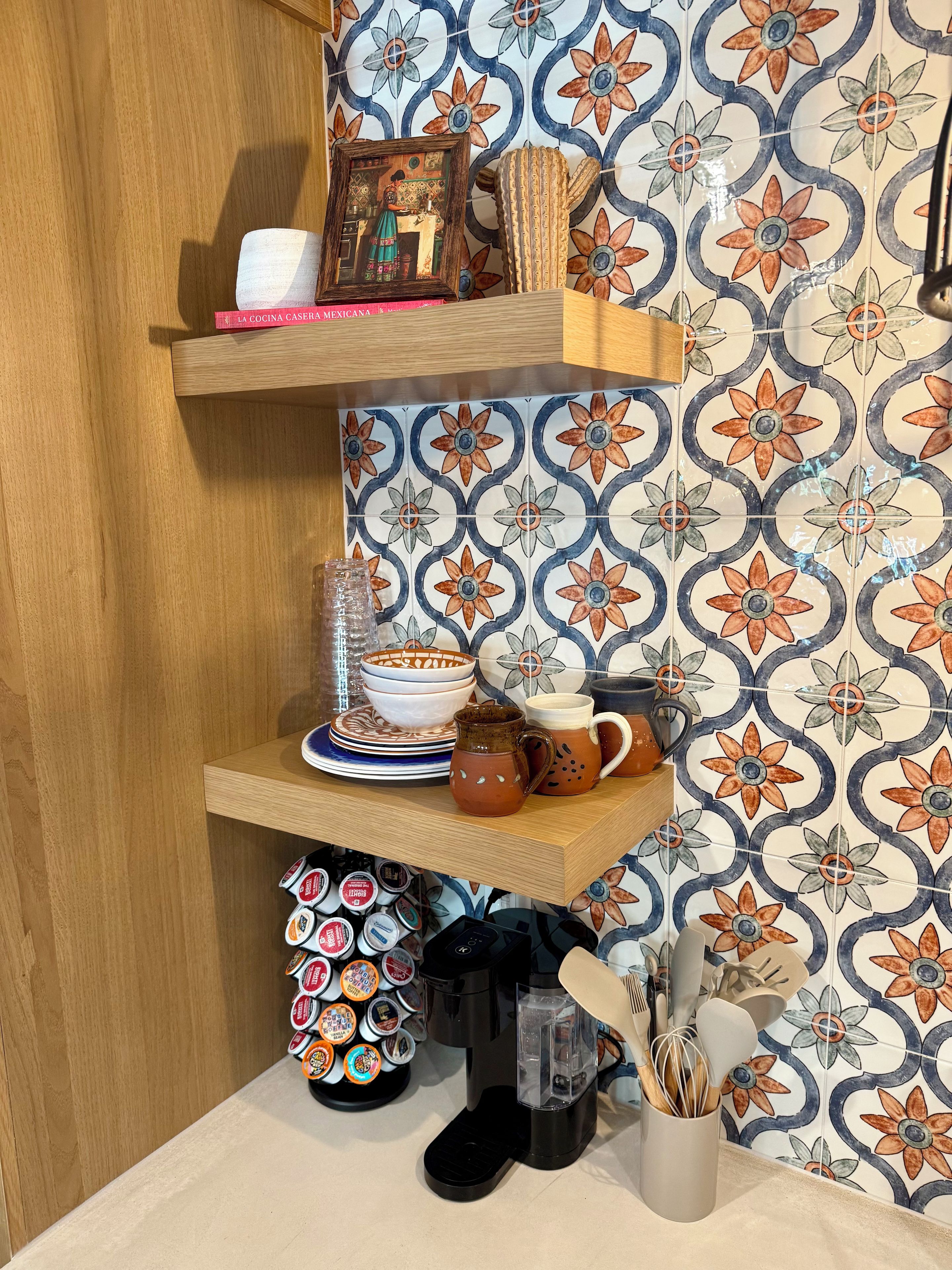 A kitchen area with a wooden shelf holding a picture frame, a book, and kitchenware.
