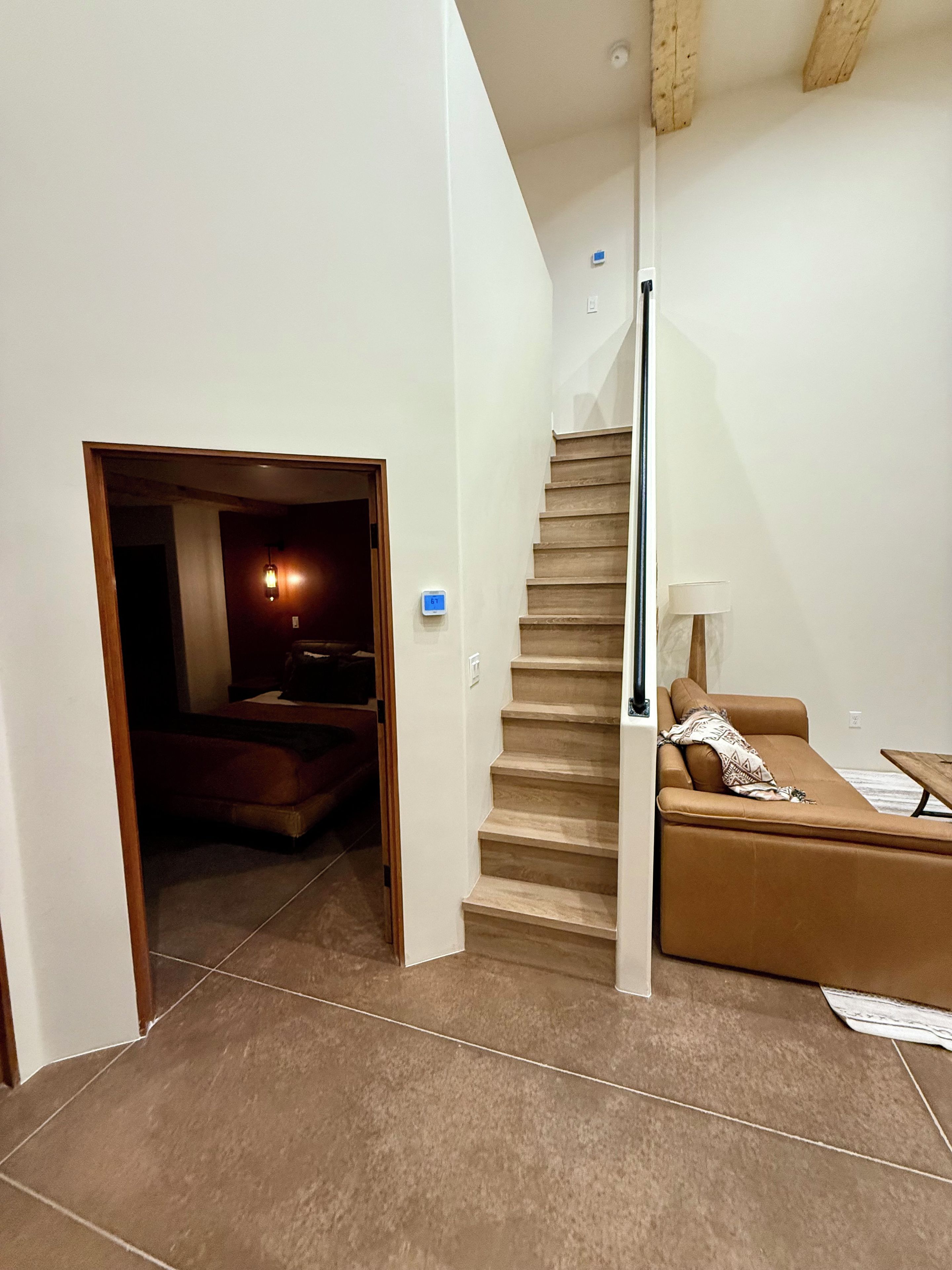Una escalera conduce a una sala de estar con un sofá y una lámpara.