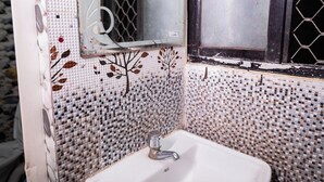 A bathroom with a white sink, a mirror, and a window with a mesh screen. - Hotel Sriram Guest House OD (Puri)