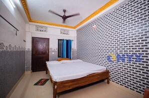 Ein Schlafzimmer mit einem hölzernen Bett, einem Deckenventilator, einer Tür und Wandverkleidung mit Muster.