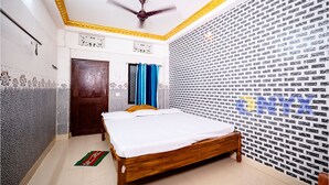 A bedroom with a bed, a ceiling fan, a door, and patterned walls. - Hotel Sriram Guest House OD (Puri)