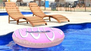 Ein Swimmingpool mit Liegestühlen und einem rosa Schwimmreifen.