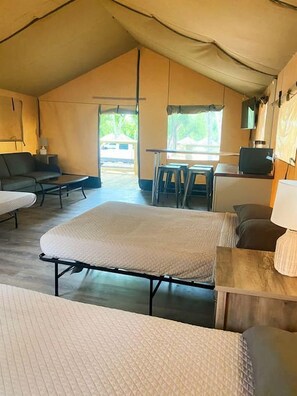 A tented accommodation with a bed, sofa, and table. - Unplug and Reconnect: Creekside Safari Tent Glamping in Cibolo, Texas (Cibolo)