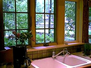 A bathroom with a window, sink, and a vase with flowers. - All Season Romantic One-Room Cabin on Moody Pond, in Upstate New York (Saranac Lake)