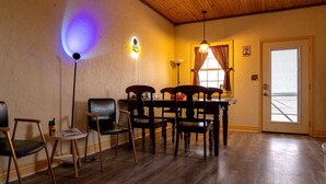 Ein Zimmer mit Holzboden, einem Esstisch mit Stühlen, einer Lampe und einer Tür mit Fenster.