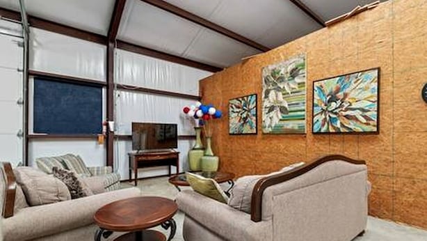 Een woonkamer met een bank, salontafel en kunstwerk aan de muur.