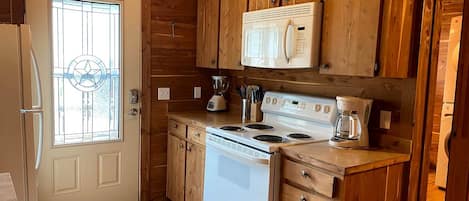 Una cocina compacta con armarios de madera, estufa blanca y cafetera.