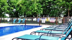 Una piscina con agua azul, rodeada por una valla y tumbonas.