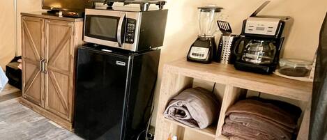 Cocina compacta equipada con refrigerador, microondas, licuadora y cafetera.