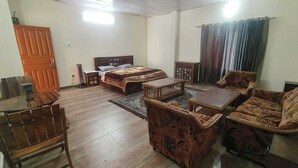 A room with a bed, a dining table with chairs, a sofa, and a small table.