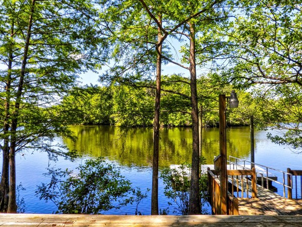 Une jetée en bois s’étendant sur un lac paisible, entouré de grands arbres.