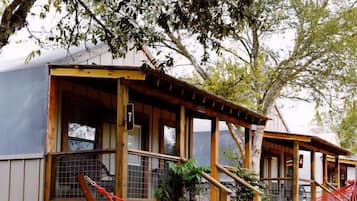 A rustic outdoor area with a fire pit, a hammock, and wooden structures.