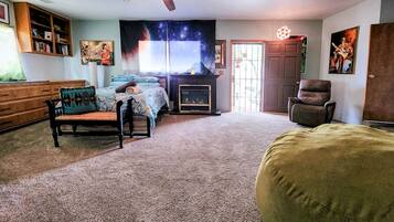 A room with a fireplace, a ceiling fan, a sofa, a chair, and a large window.
