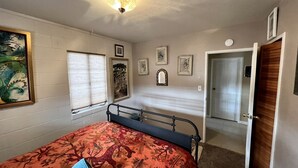 Un dormitorio con cama, ventana con persianas, puerta y un aplique de pared.