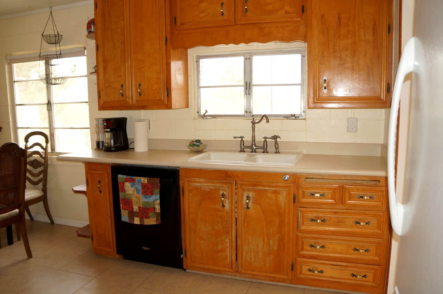 A kitchen with wooden cabinets, a dishwasher, a sink, and a window.