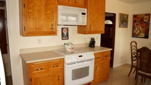 Una cocina con armarios de madera, un microondas, una estufa y un hervidor.