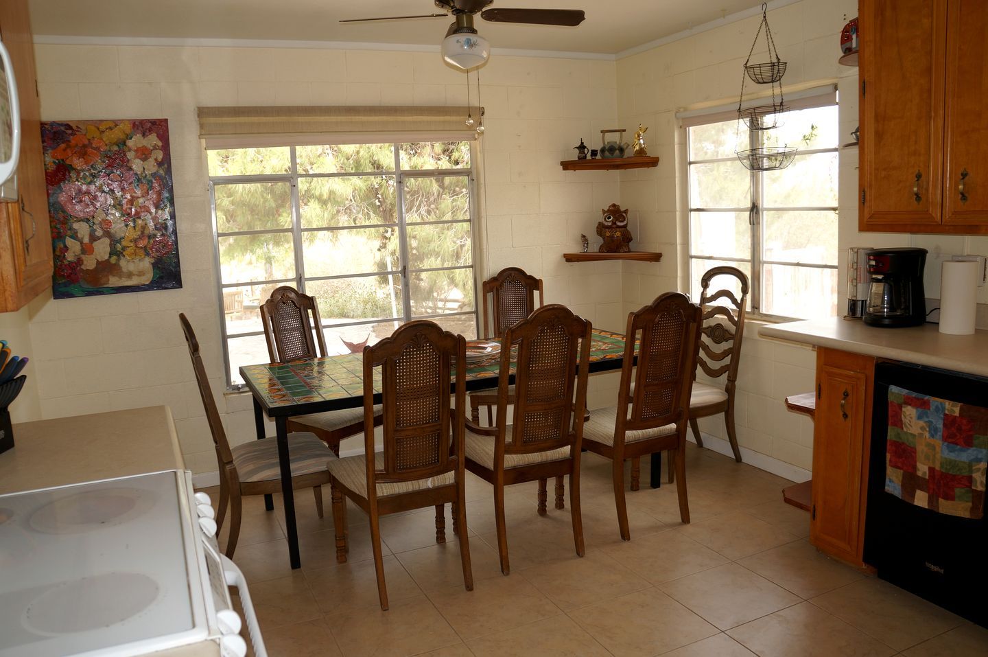 A kitchen with a dining table, chairs, a stove, and a ceiling fan.