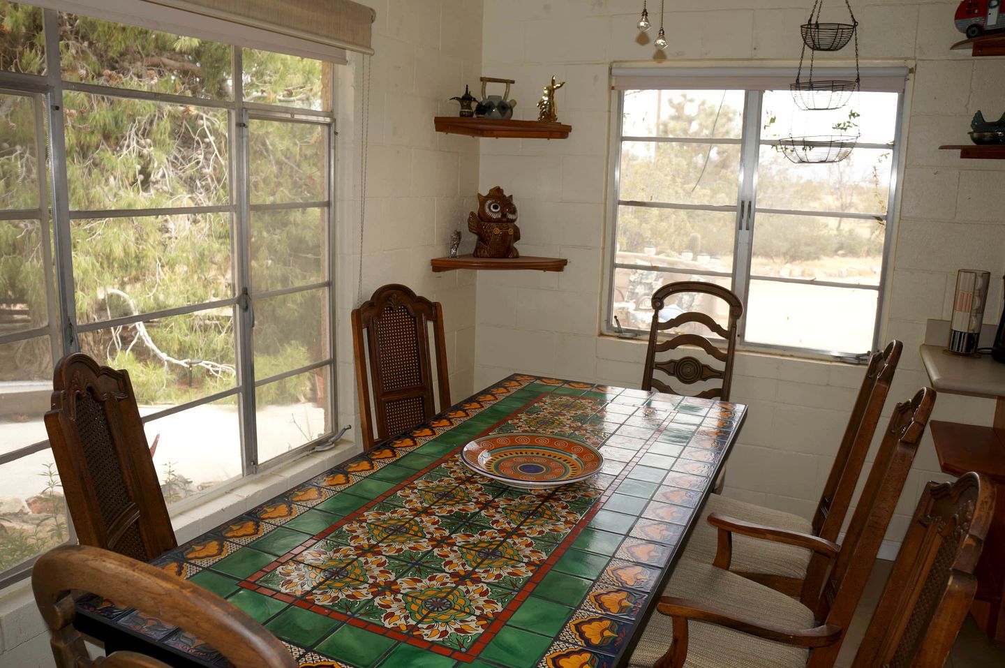 Un comedor con una mesa larga, sillas y ventanas grandes.
