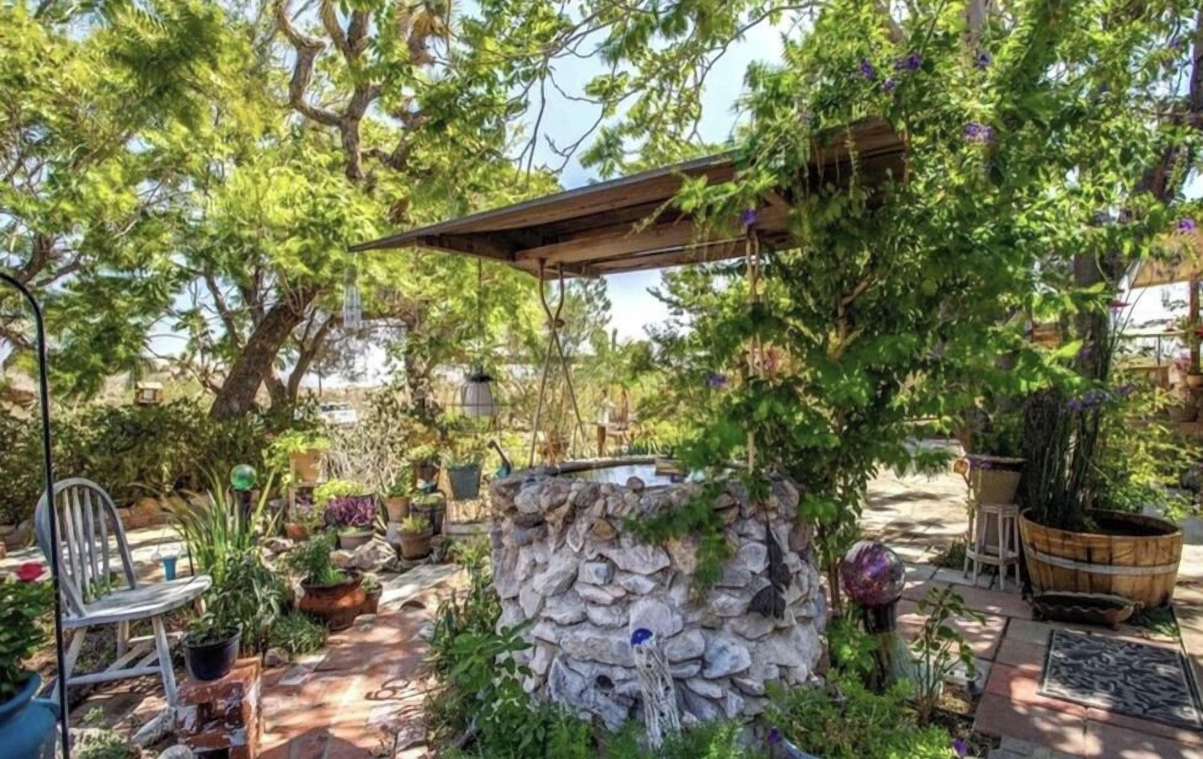 A garden with a stone wall, potted plants, and a wooden pergola.