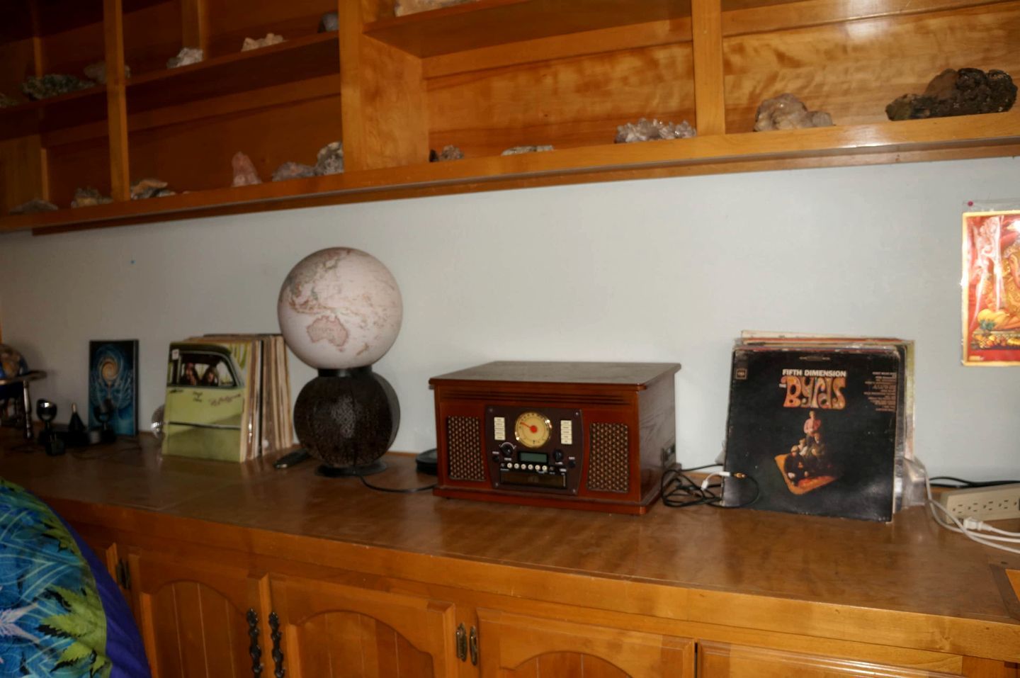 A wooden shelf with a globe, a radio, and a vinyl record.