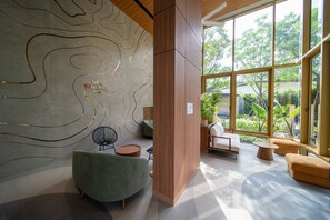 Un interior moderno con un diseño de pared curva, paneles de madera y una zona de estar con vistas a la vegetación.