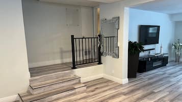 Un escalier avec des marches en bois et des rampes noires, un téléviseur à écran plat fixé au mur et une plante en pot.