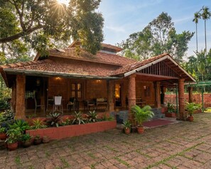 A traditional building with a tiled roof, a covered porch, and a brick pathway. - Vilstay Premium Panthalaza  (Narinada)