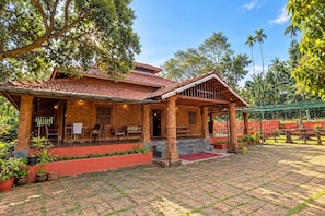 A traditional house with a tiled roof, a covered porch, and a brick pathway leading to the entrance. - Vilstay Premium Panthalaza  (Koyilandy)