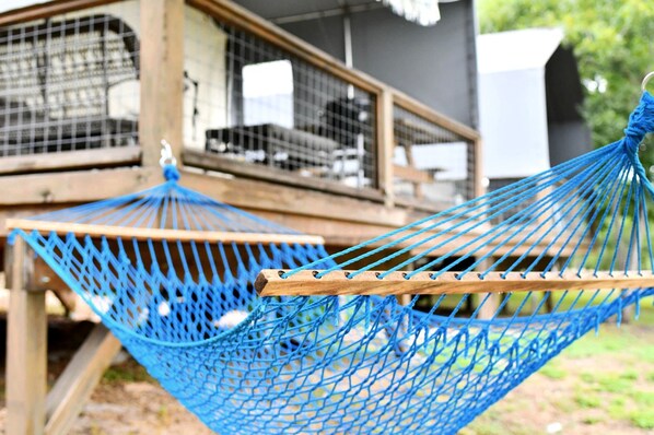 A blue hammock tied to a wooden structure with a view of a building in the background.