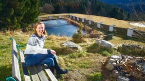 Une personne est assise sur un banc, d’où elle a une vue sur un étang bordé d’une clôture en bois et de rochers.
