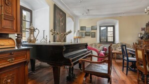 Une pièce avec un grand piano, des meubles en bois et des œuvres d’art encadrées accrochées aux murs.