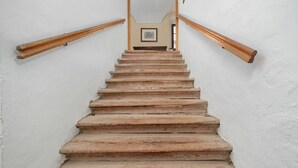 Un escalier en bois, avec un mur blanc et un tableau encadré en haut.