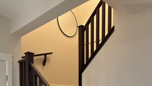 Una escalera con barandillas de madera oscura y escalones alfombrados color beige.