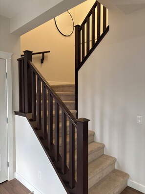 Eine Treppe mit dunklen Holzgeländern und beige belegten Stufen.