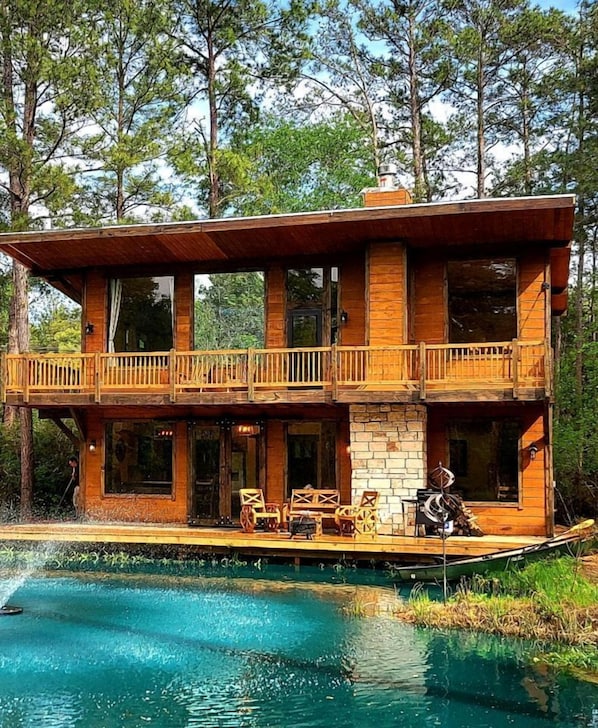 Eine zweistöckige Holzhütte mit einem Balkon, einem Pool und Gartenmöbeln.