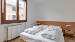 Una camera da letto con un letto, un comodino, una finestra e un termosifone.