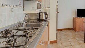 Una cucina con piano cottura a gas, lavello in acciaio inossidabile e forno a microonde.