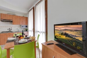 Una cocina moderna con armarios de madera, un microondas y un comedor con una mesa para dos.