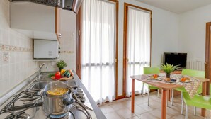 Eine Küche mit Herd, Spüle und einem Essbereich inklusive Tisch und Stühlen.