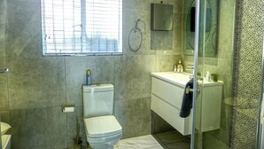 Un baño moderno con inodoro, lavamanos y zona de ducha.
