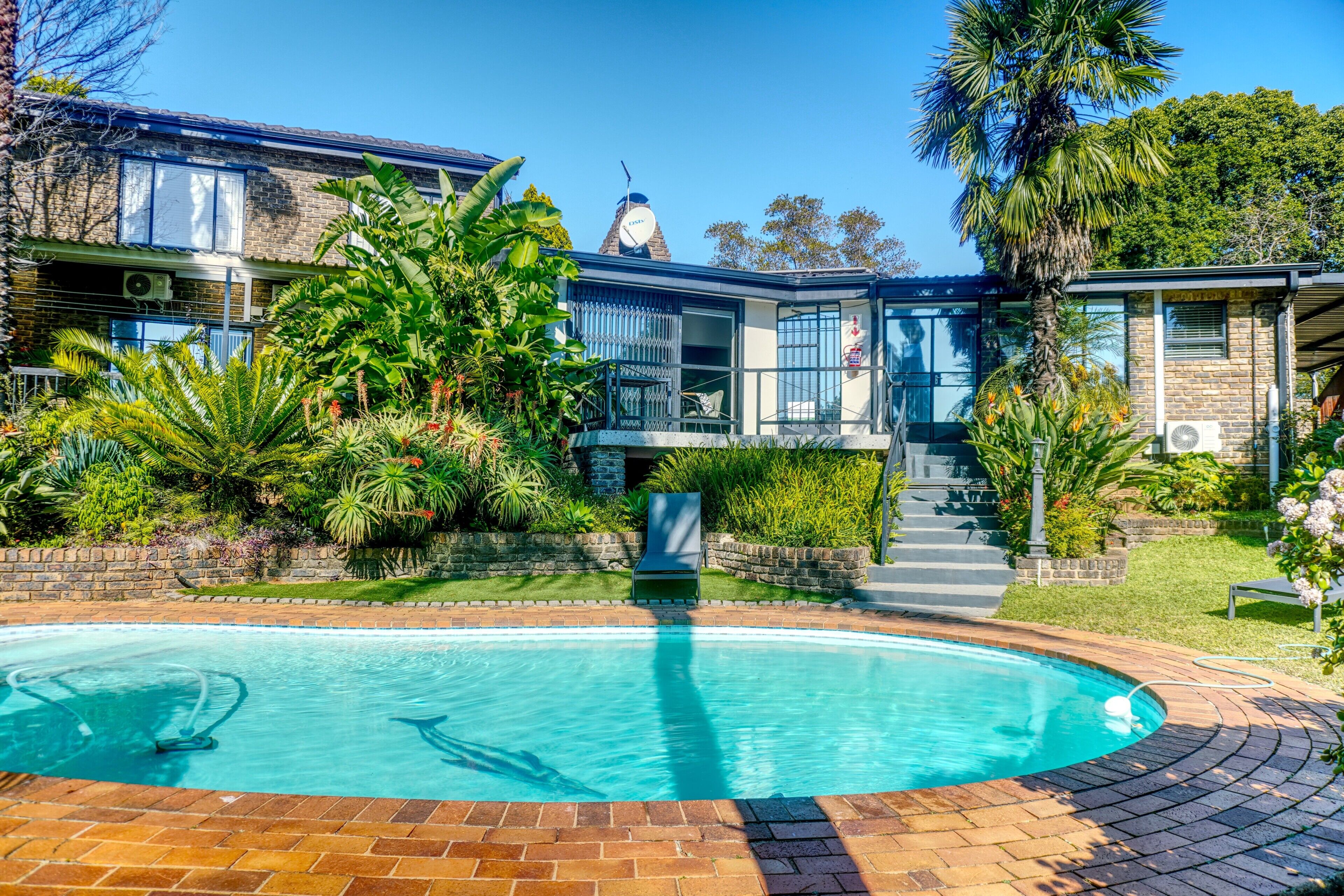 A residential property with a swimming pool, a stone staircase, and lush greenery.