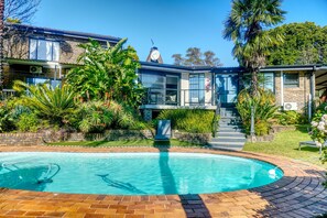 A residential property with a swimming pool, a stone staircase, and lush greenery.