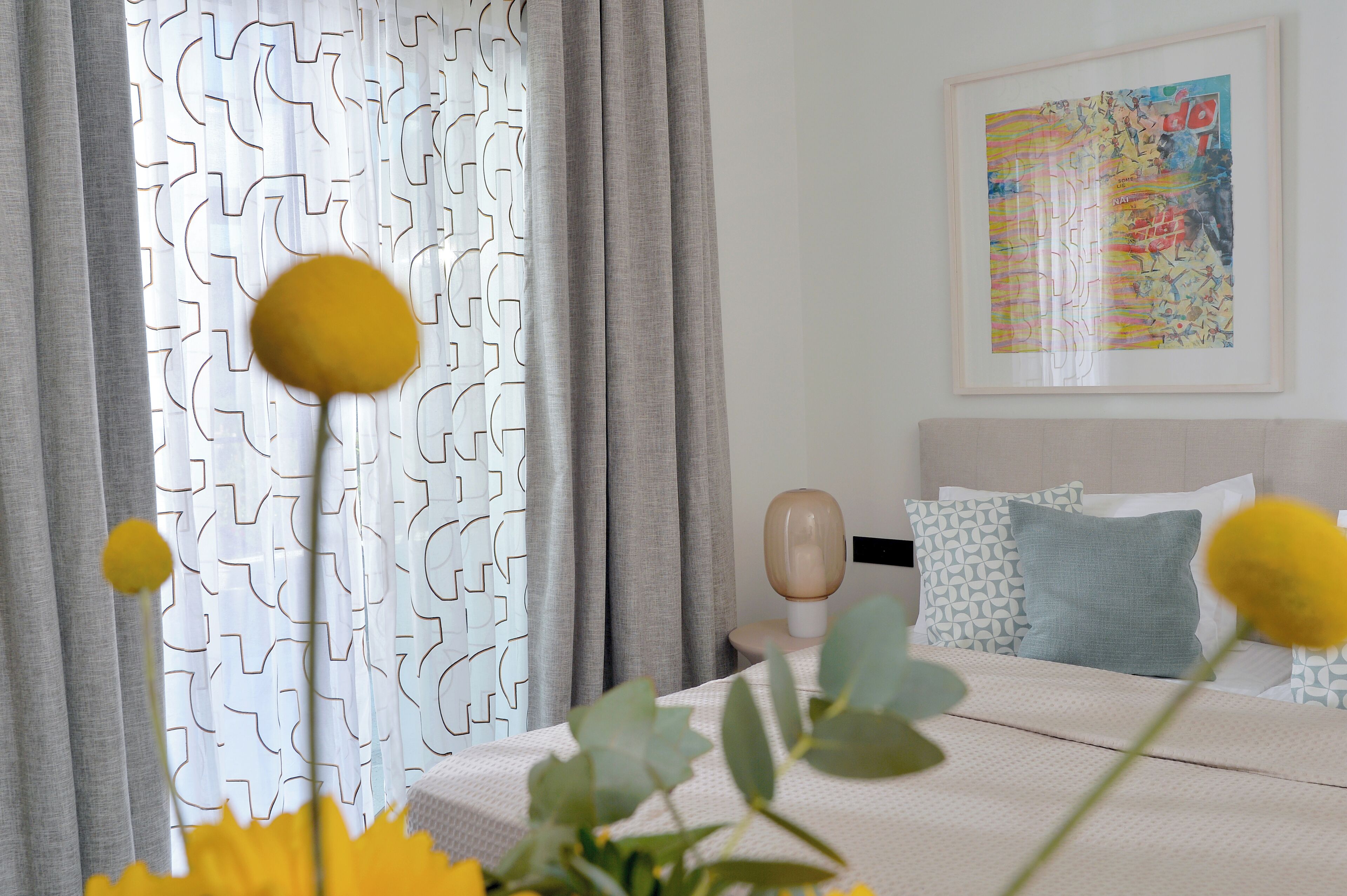 A bedroom with a bed, a nightstand, a lamp, and a painting on the wall.