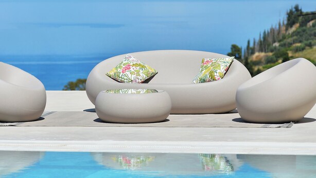 A poolside area with a sofa and ottoman, a clear view of the sea, and a mountainous landscape in the background. - Althea Resorts (Xylokastro-Evrostina)